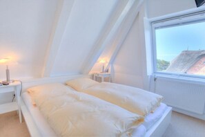 Een slaapkamer met een bed, nachtkastjes en een raam met uitzicht.