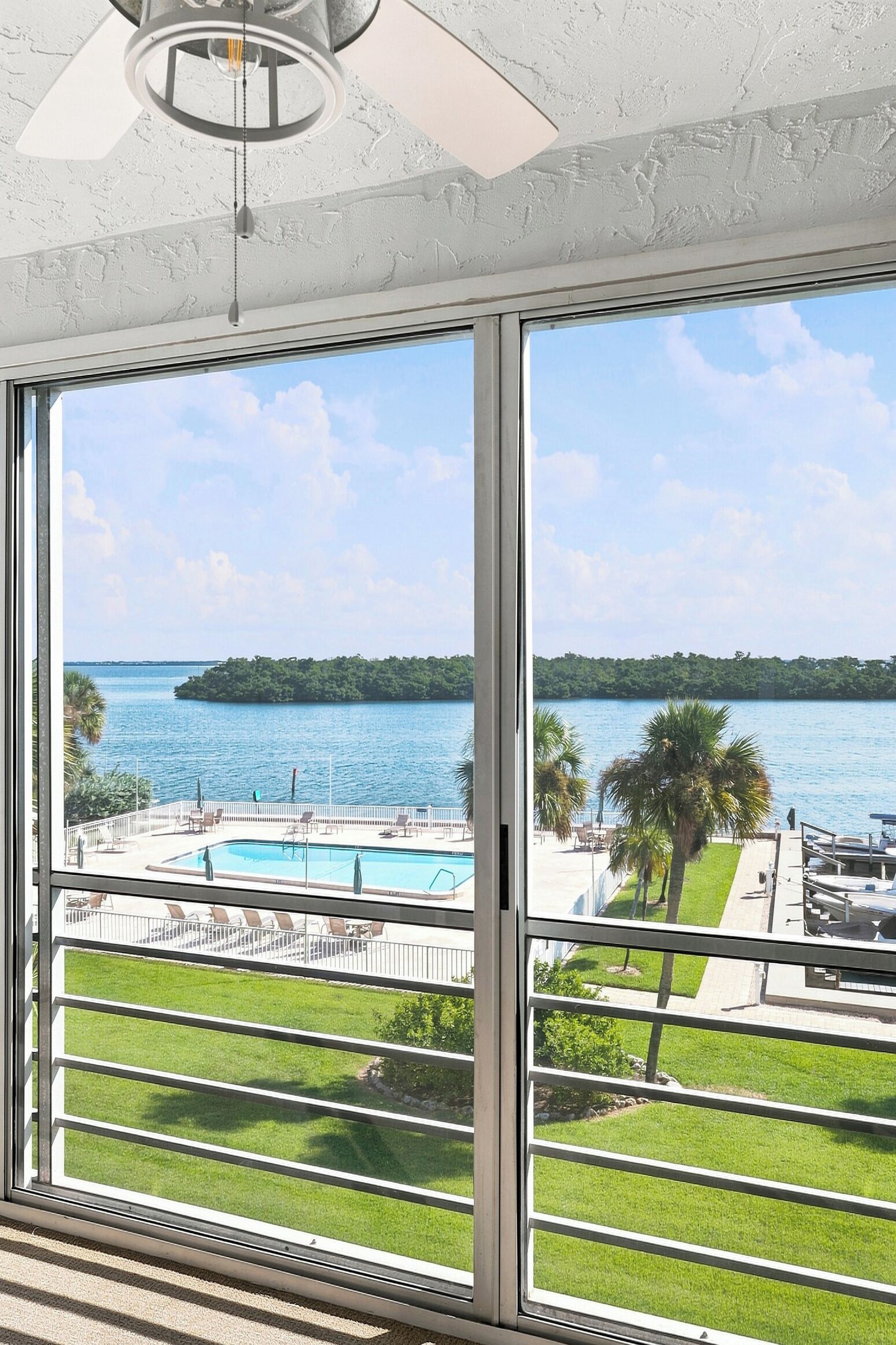 A room with large windows overlooking a pool and a body of water.