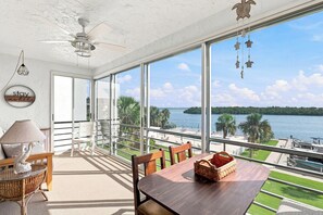 Un balcón amplio con vista a un lago, una mesa de comedor con sillas y un ventilador de techo.