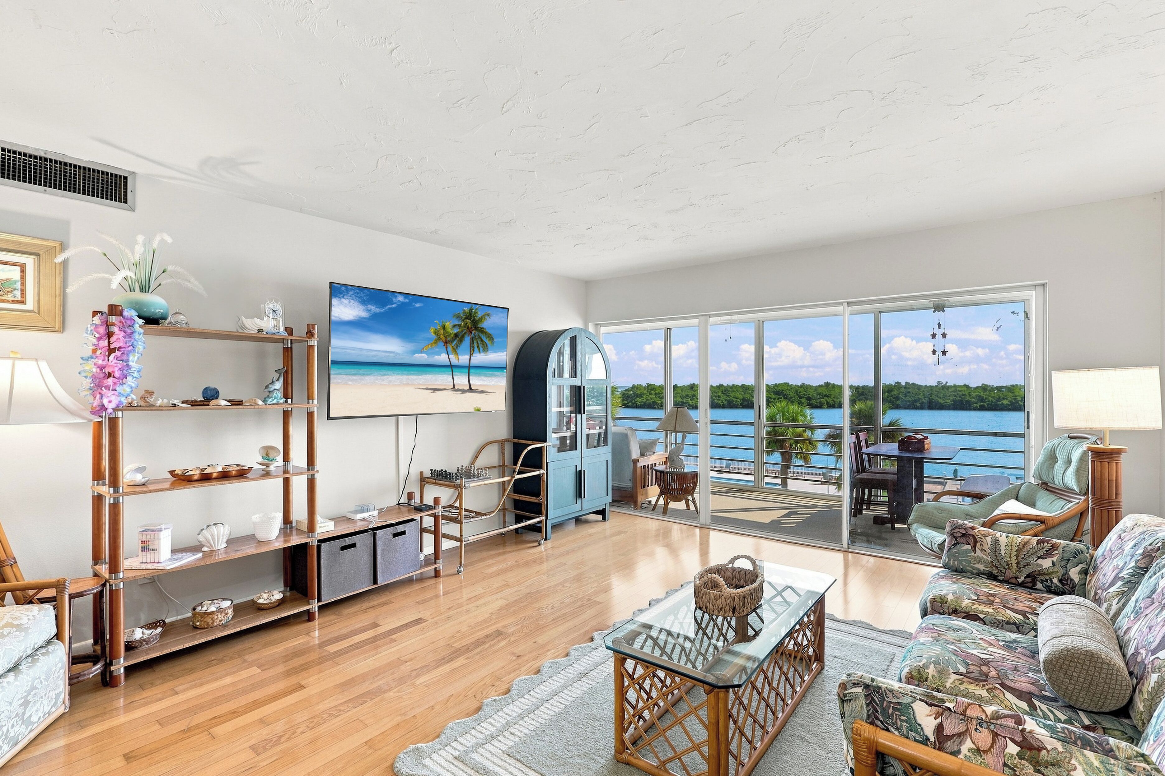 A spacious living room with a large window offering a view of a body of water, a television, and a dining area with a view.