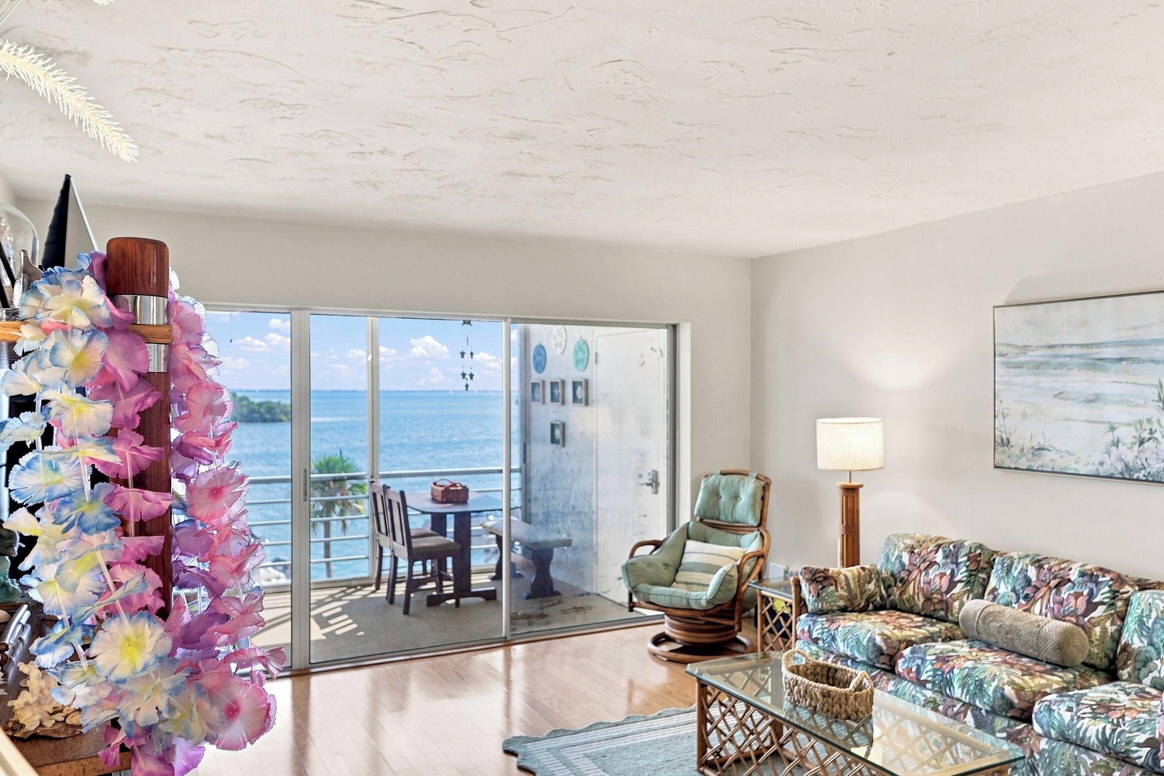 A room with a view of the sea, a chair, a sofa, and a table.