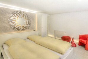 Ein modernes Hotelzimmer mit einem Bett, einem roten Sessel und einer außergewöhnlichen Wanddekoration.
