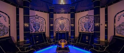 Ein luxuriöses Zimmer mit zentralem Pool, aufwendigen Wandverzierungen und einer Sternenhimmel-Decke.