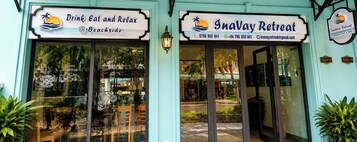 Establecimiento frente a la playa con un letrero que dice 'Drink, Eat and Relax @ Beachside' e 'Inava Retreat'.