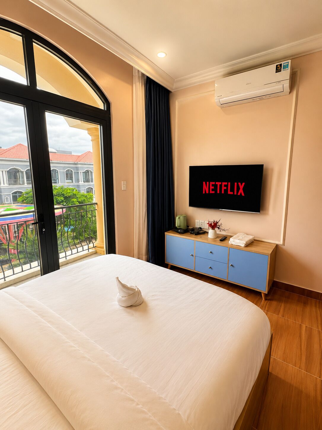 Habitación de hotel con cama, televisor montado en la pared, minibar y vista a un patio.