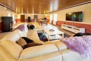 A spacious living room with a sofa, coffee table, and a flat-screen TV mounted on the wall. - Holiday home with 1 bedroom (Bernkastel-Kues)