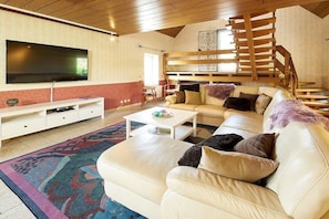 Ein Wohnzimmer mit einer Couch, einem Couchtisch, einem Fernseher und einer Treppe.
