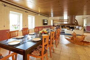 A dining area with a long table, chairs, and a television mounted on the wall. - Holiday home with 1 bedroom (Bernkastel-Kues)
