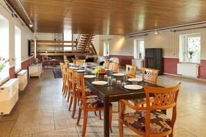 Een ruime eetruimte met een lange tafel, meerdere stoelen en een trap op de achtergrond.