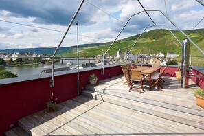 Eine Holzterrasse mit Tisch und Stühlen mit Blick auf einen Fluss und eine Stadt.