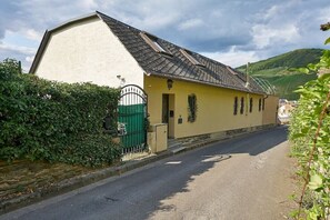 Ein eingeschossiges Gebäude mit einem geneigten Dach, einem grünen Tor und einer gepflasterten Straße davor.