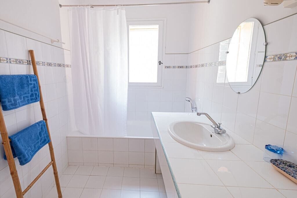 A bathroom with a bathtub, a sink, a mirror, and a towel rack.