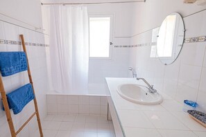 Ein Badezimmer mit Badewanne, Waschbecken, Spiegel und Handtuchhalter.
