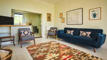 A living room with a blue sofa, two armchairs, a patterned rug, and a television on a stand.