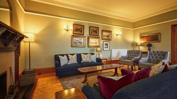 A traditional living room with a dark blue sofa, a wooden coffee table, and two armchairs.
