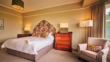 A bedroom with a bed, a dresser, a chair, and two wall-mounted lamps.