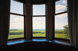 Una habitación con ventanal que da a un paisaje verde.