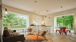 A modern kitchen with a dining area, large windows, and a view of greenery. - Kinclune House & Cottages - Sleeps 28 (Kirkton of Kingoldrum)