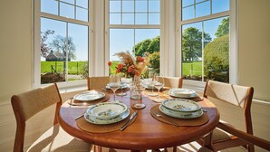 A dining table set for four with plates, glasses, and a vase of flowers. - Kinclune House & Cottages - Sleeps 28 (Kirkton of Kingoldrum)