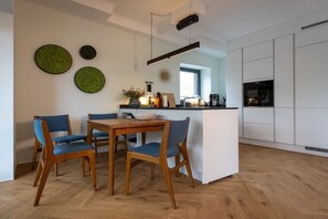 A modern kitchen with a dining area, wooden chairs, a central island, and a pendant light. - Holiday apartment with 1 bedroom (Wildeshausen)