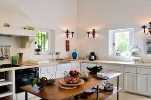 A modern kitchen with white cabinetry, a wooden island, and a window providing natural light. - Holiday home in Apt with swimming pool (Apt)