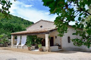 A building with a covered porch, potted plants, and a stone wall. - Holiday home in Apt with swimming pool (Apt)
