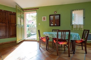 A dining area with a table and chairs, a wooden door, and a window with a lace curtain. - In a quiet location in the Luberon - 219 ROU (Gargas)