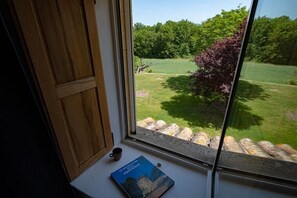 A window with a view of a garden, a book titled 'Le Grand Atlas de la Provence' on a windowsill, and a wooden door. - Holiday home with 4 bedrooms (Roussillon)