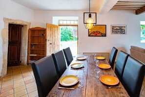 A dining area with a wooden table set for six, black chairs, and a hanging light fixture. - Holiday home with 4 bedrooms (Roussillon)