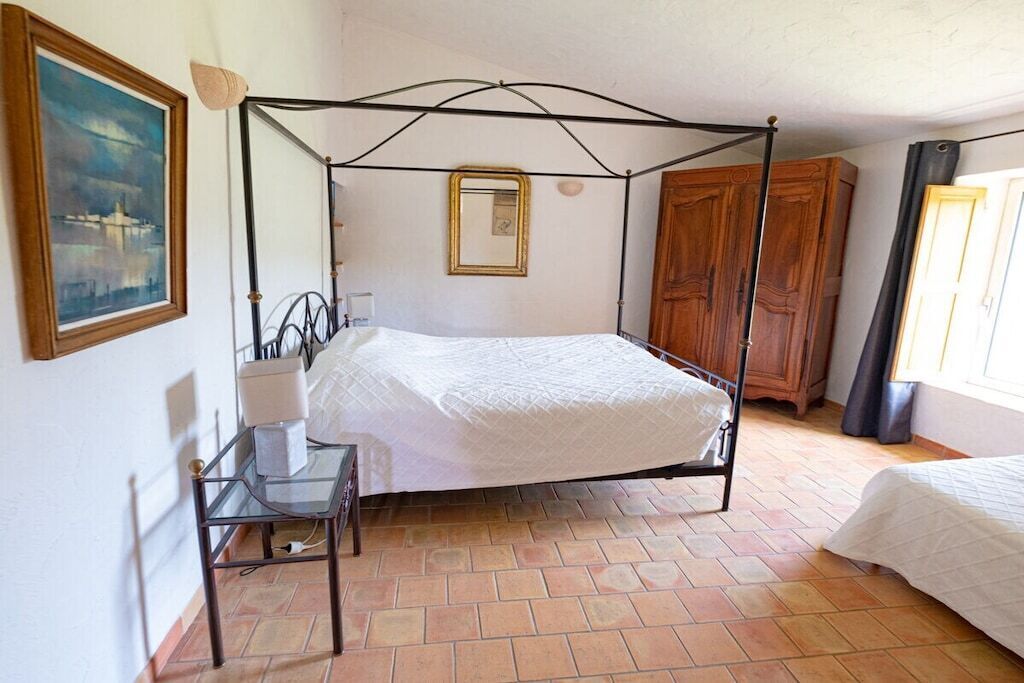 Un letto a baldacchino in una stanza con pavimento piastrellato, un armadio in legno e un quadro incorniciato appeso al muro.