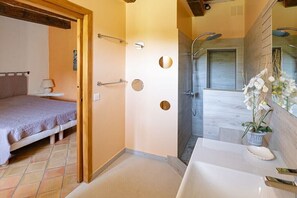 A bathroom with a shower, a sink, and a bed in the adjacent room. - Holiday home with 4 bedrooms (Roussillon)