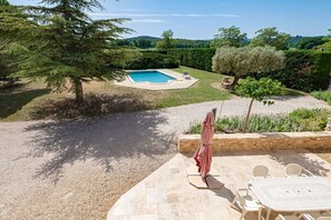 A backyard with a swimming pool, a patio table, and a covered seating area. - Holiday home with 4 bedrooms (Roussillon)