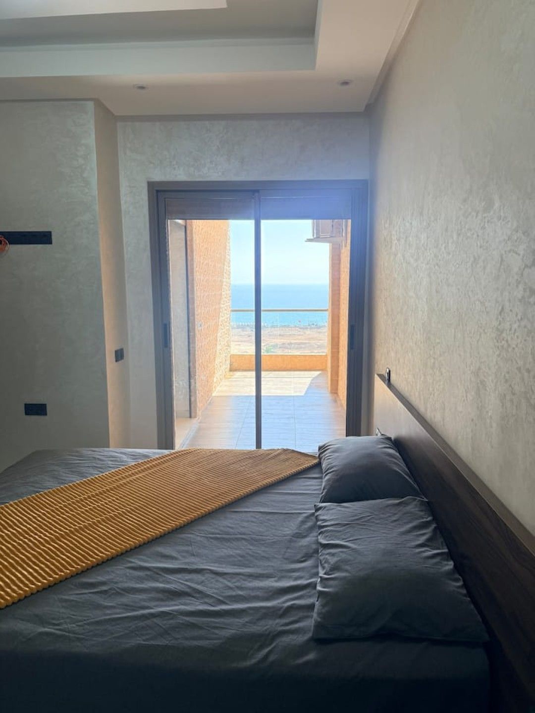 A bedroom with a bed, a view of the beach, and a door leading to an outdoor area.