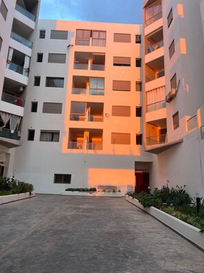 A multi-story residential building with balconies, a central courtyard, and a flat facade. - Elegant 3 bed apartment with sea view (Anza)