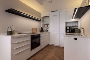 Een moderne keuken met witte kasten, een ingebouwde oven en een roestvrijstalen afzuigkap.