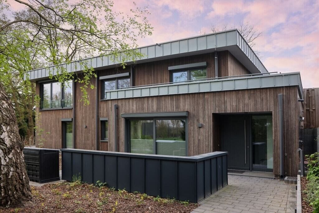 Un bâtiment moderne à deux étages, doté d’une façade en bois, de grandes fenêtres et d’un mur extérieur de couleur noire.
