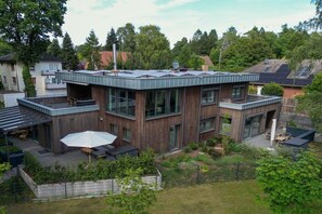 A modern two-story house with a flat roof, large windows, and a covered outdoor seating area. - Holiday apartment with 1 bedroom (Wildeshausen)