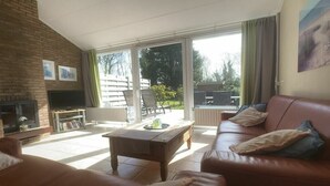 A living room with a fireplace, a sofa, a coffee table, and a television. - Holiday home with 3 bedrooms (Cadzand-Bad)