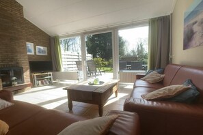 A living room with a fireplace, a sofa, a coffee table, and a television. - Holiday home with 3 bedrooms (Cadzand-Bad)