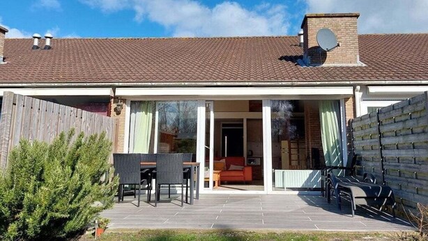 A residential property with a covered patio, a brick chimney, and a sliding glass door leading to an interior space. - Holiday home with 3 bedrooms (Cadzand-Bad)