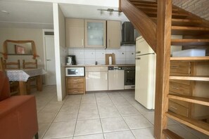 A kitchen with wooden cabinets, a dishwasher, and a refrigerator. - Holiday home with 3 bedrooms (Cadzand-Bad)