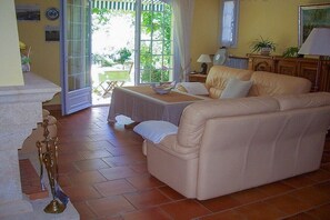 A living room with a sofa, a table, and a window with a view of greenery. - Holiday apartment with 1 bedroom (Cavaillon)