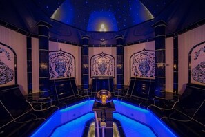 Ein luxuriöses Zimmer mit einem beeindruckenden Kronleuchter, aufwendigen Wandverzierungen und einer sternenübersäten Decke.