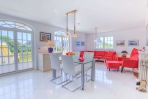 Un salon spacieux avec une table en verre, un canapé rouge et de grandes fenêtres.