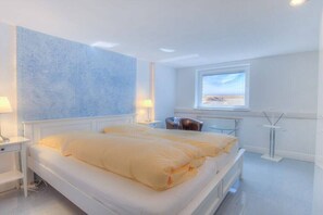 Ein modernes Schlafzimmer mit einem großen Bett, Nachttischlampen, einem Fenster mit Blick und einer Heizung.