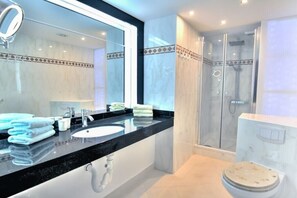 Ein modernes Badezimmer mit großem Spiegel, Waschbecken, Toilette und einer Duschkabine.