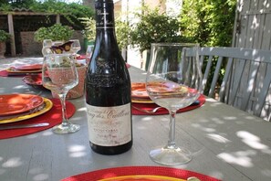 A bottle of wine on a table with glasses and plates, suggesting a dining setting. - Holiday home in Sarrians with swimming pool (Sarrians)