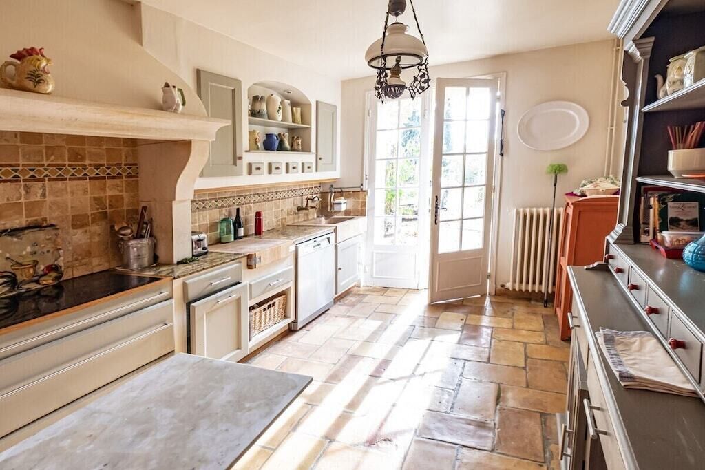 Une cuisine avec un mur recouvert de carreaux, un îlot central et une porte donnant sur un espace extérieur.
