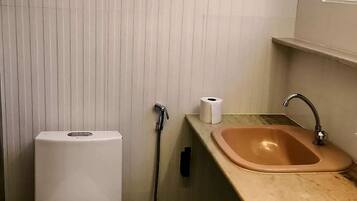 A small bathroom with a toilet, a sink, and a shower.