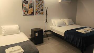 Una habitación de hotel con dos camas, un pequeño calentador negro y dos unidades de aire acondicionado instaladas en la pared.